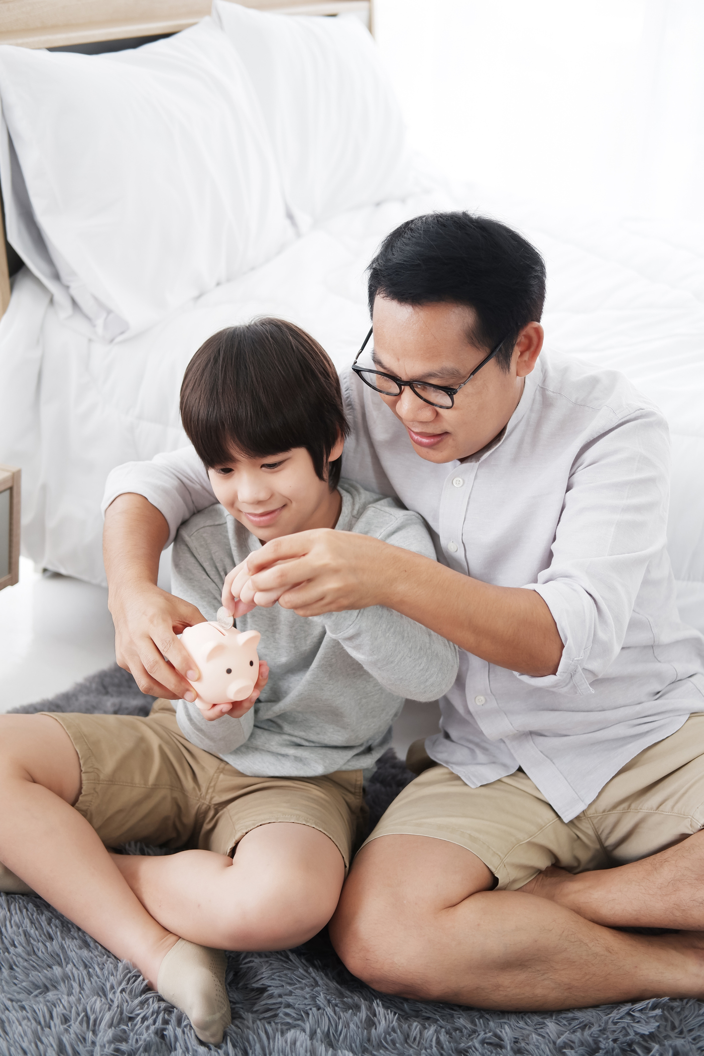 Father and son putting money in piggy bank