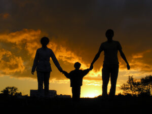 Silhouette of a family holding hands in front of a sunset